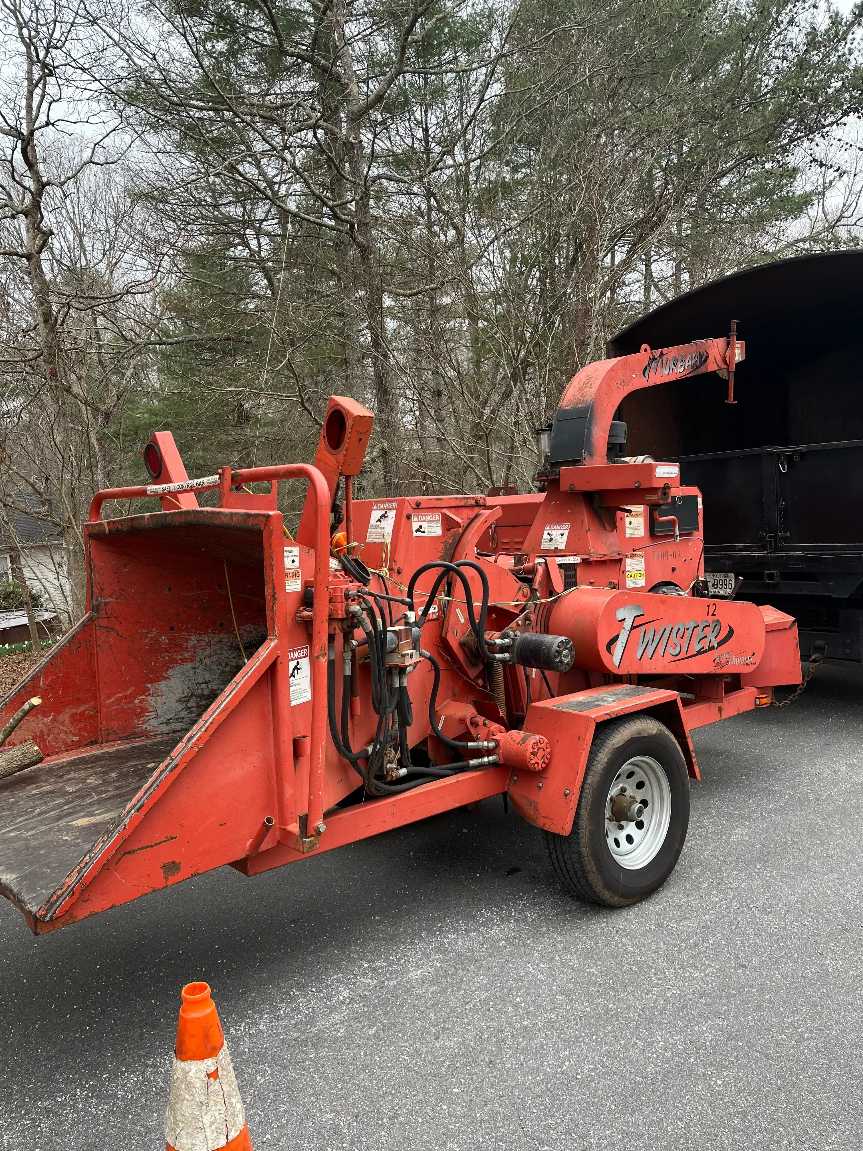 Red commercial wood chipper with hydraulic system and discharge chute