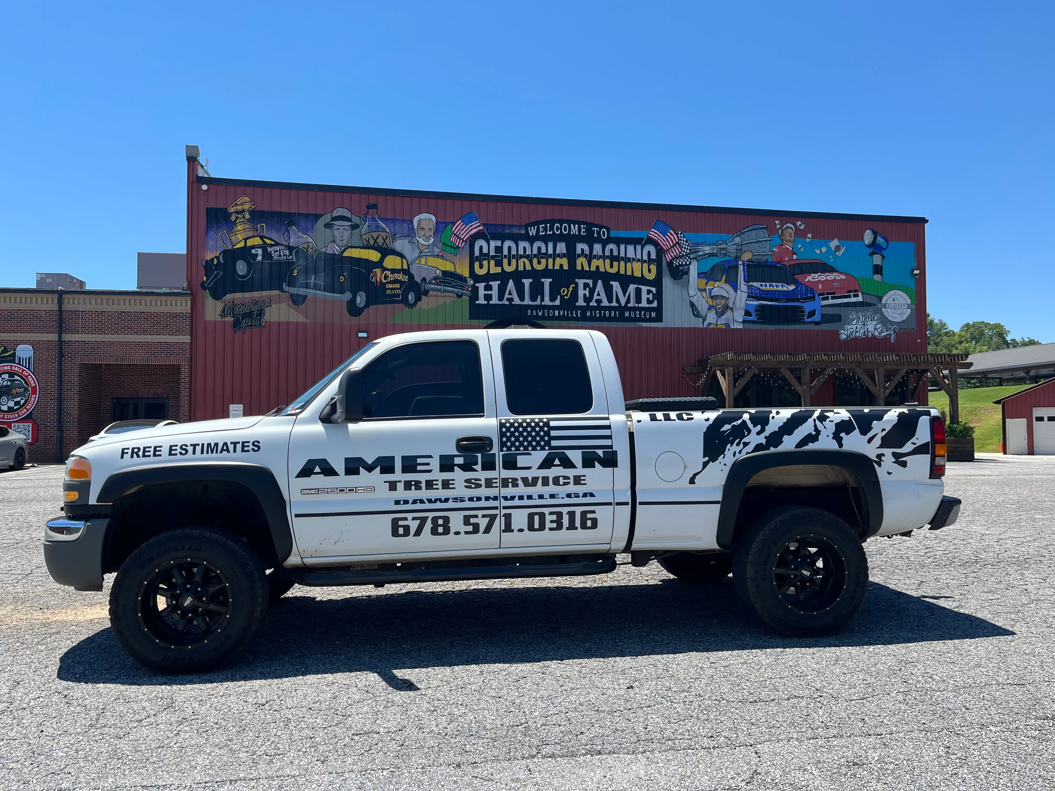 White pickup truck with custom vinyl wrap, patriotic graphics, and tree service branding